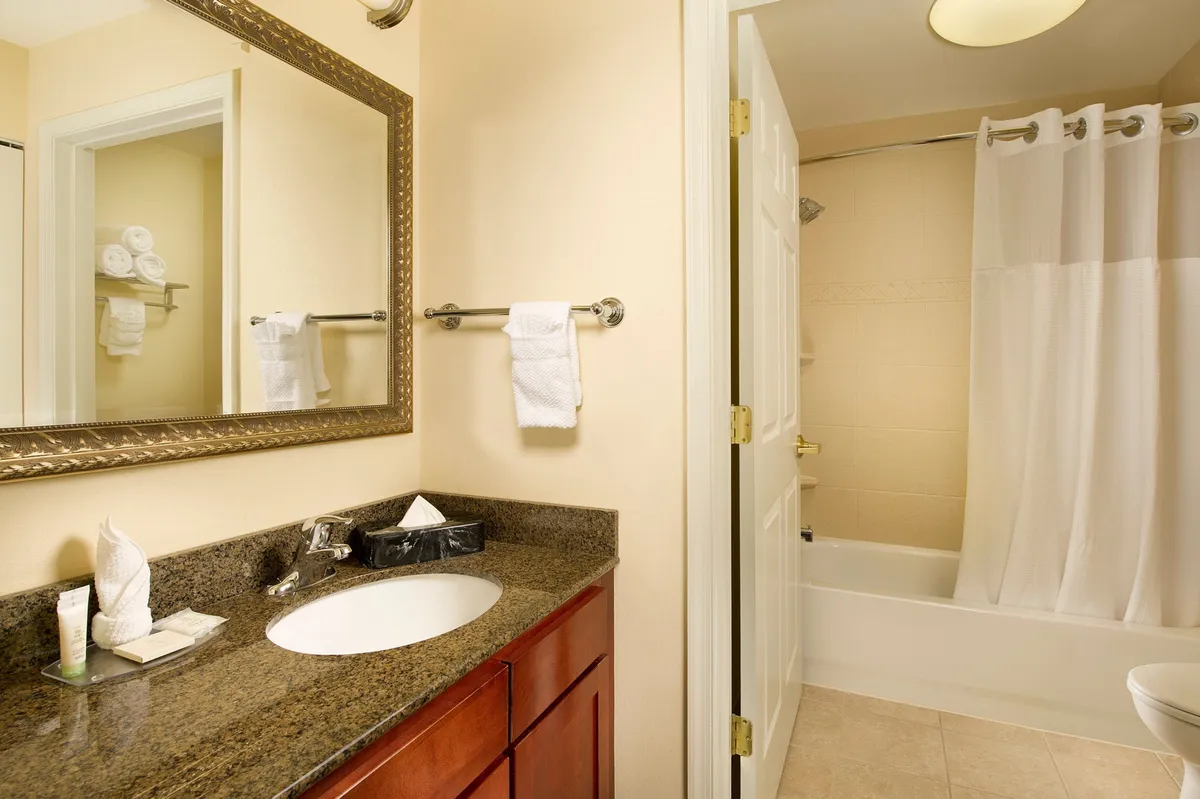 This bathroom image features a modern vanity with sink, a large mirror, shower area, and toilet space. The room is well-lit and organized, evoking a sense of cleanliness and calm. Visible amenities suggest readiness for personal care and relaxation.