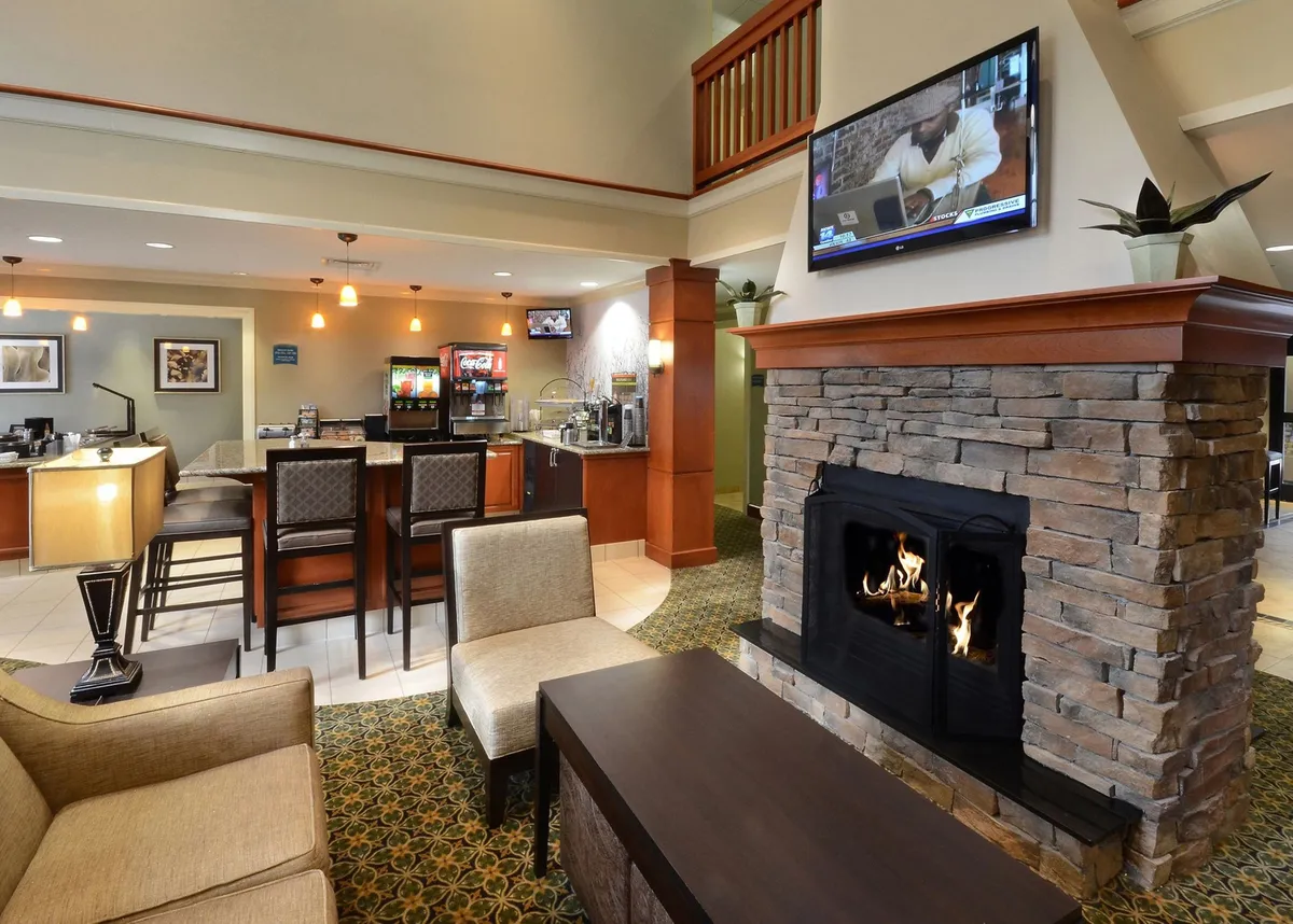 This image showcases a welcoming interior living space featuring a cozy fireplace, a comfortable seating area, a bar counter, and a television. The arrangement is inviting and suggests a space equally suited for relaxation and socializing. The visible TV and plush seating echo the amenities described in the section, while the overall atmosphere highlights comfort and adaptability.